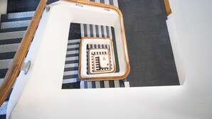 Un escalier avec une rampe en bois et une moquette à rayures noires et blanches.