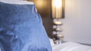 A bed with a blue pillow and white bedding.