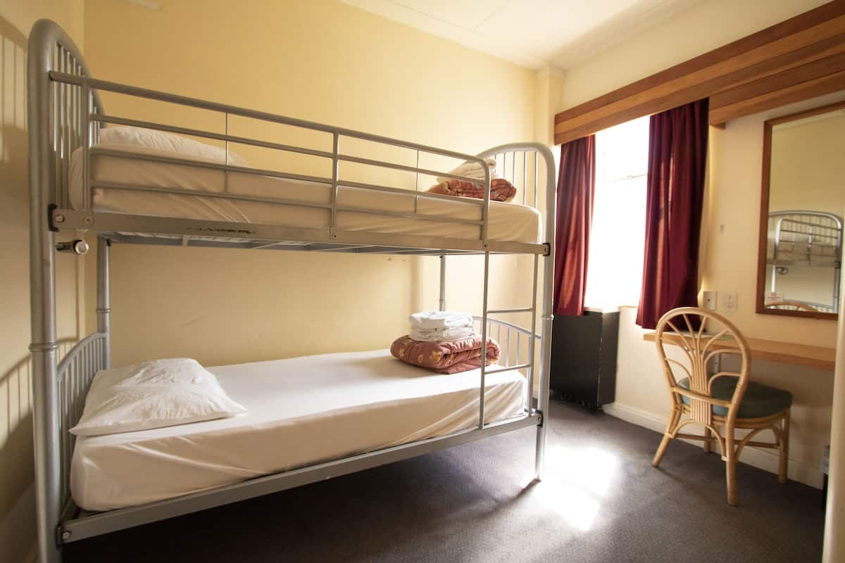 Dormitorio con literas, una silla y un espejo.