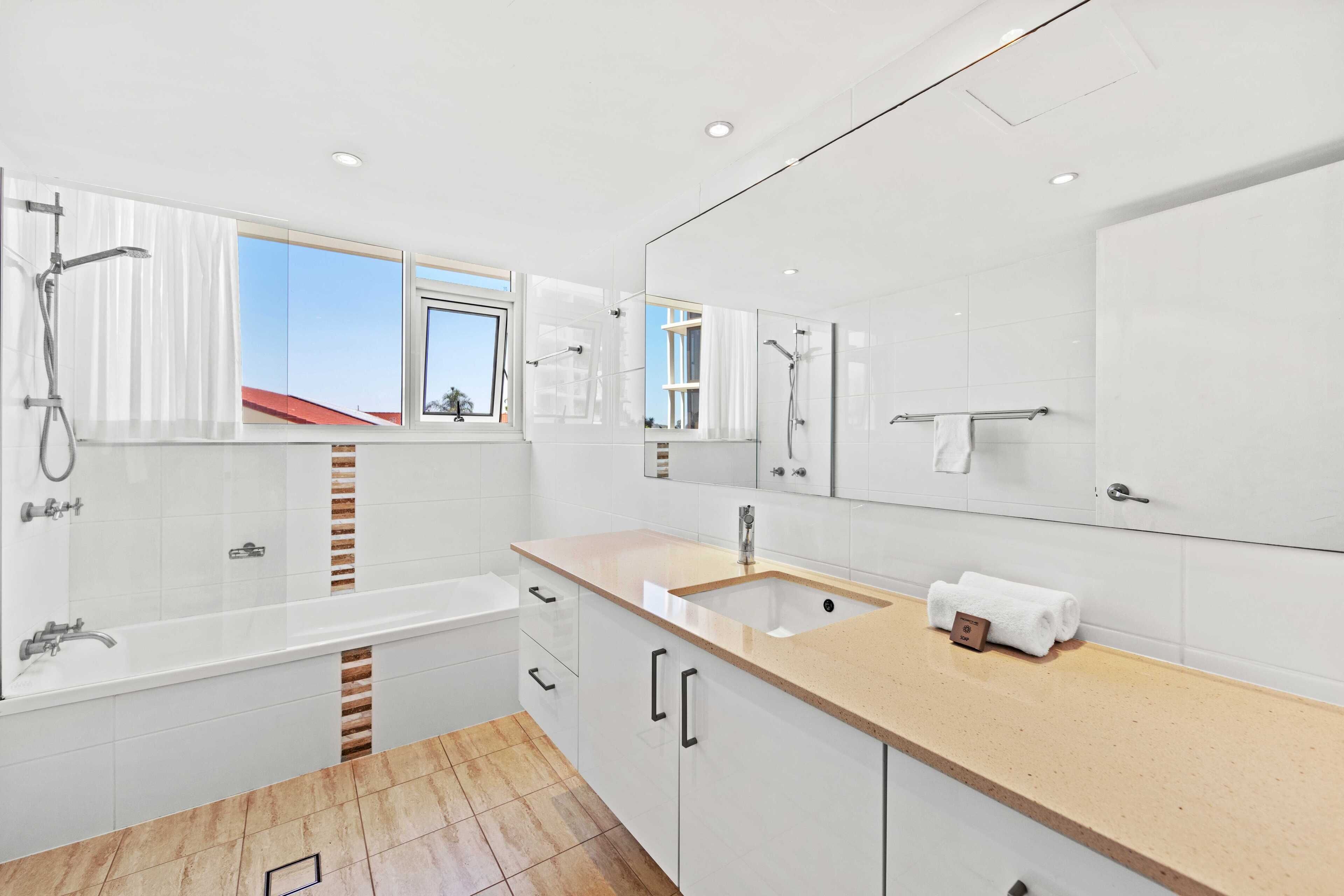 A modern bathroom with a bathtub, a sink, and a large mirror.