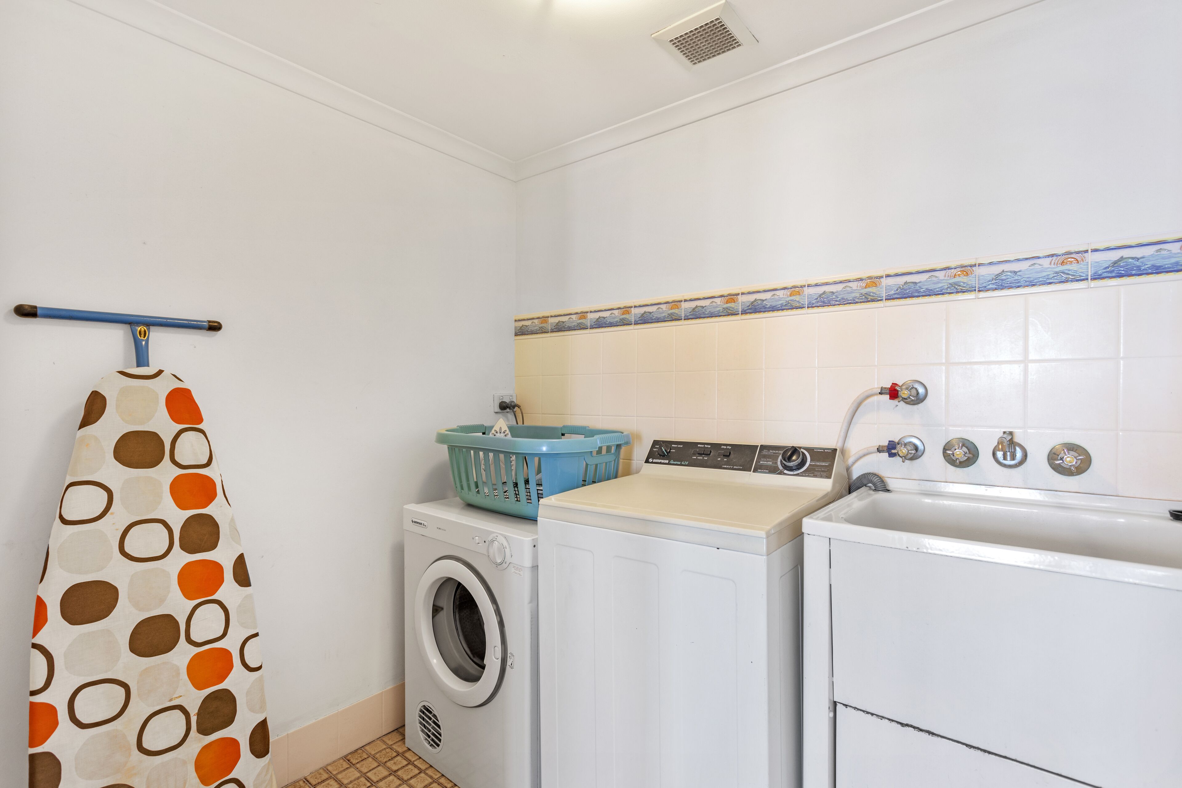 A laundry area with a washing machine, dryer, and a blue laundry basket on top of the dryer.