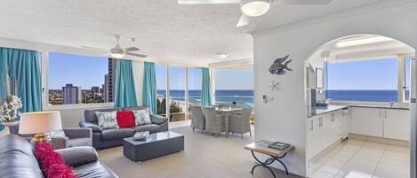 Amplia sala de estar con vista al océano, un balcón y una cocina.
