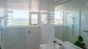 A modern bathroom with a large mirror, a shower, and a sink.