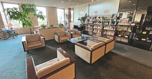 A hotel lobby with seating, a reception desk, a plant, and a display of toiletries.