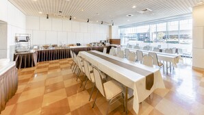 Een ruime vergaderzaal met een lange tafel, stoelen en een buffetopstelling.