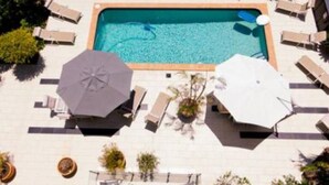 An aerial view of a swimming pool with lounge chairs and umbrellas, surrounded by greenery. - Durham Court Holiday Apartments (Surfers Paradise)