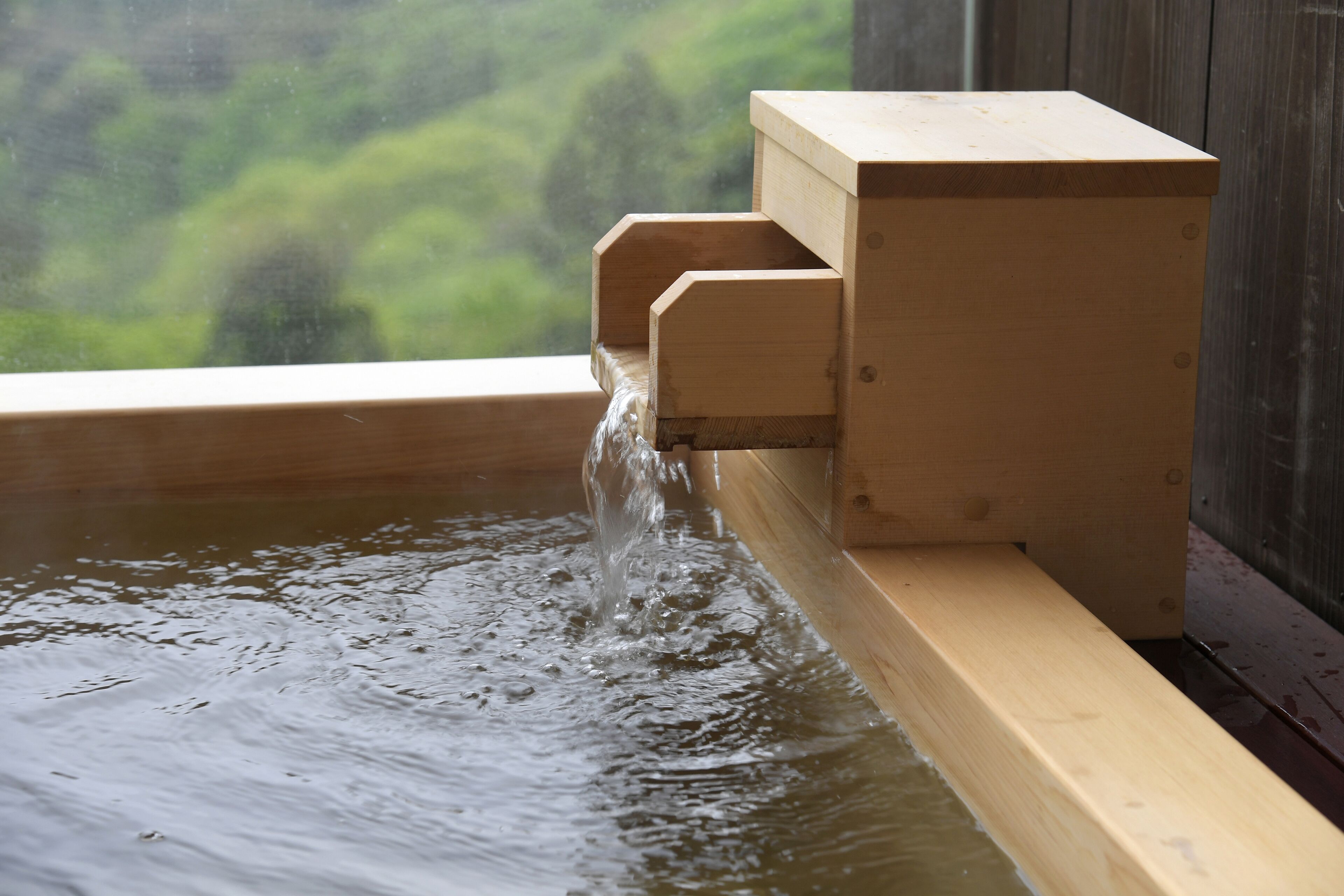 Une structure en bois d’où s’écoule de l’eau dans une piscine.