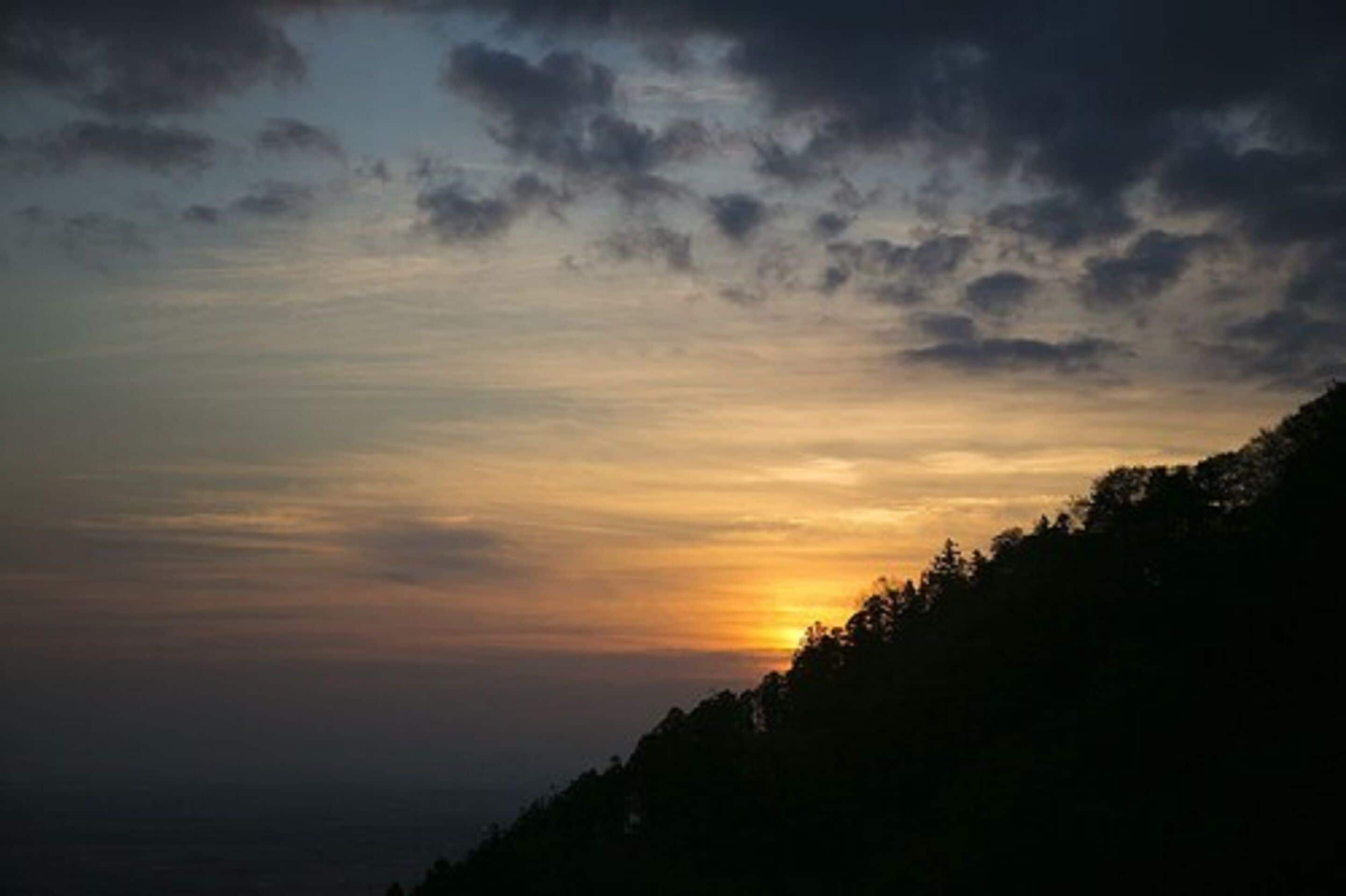 Un atardecer sobre una ladera boscosa.