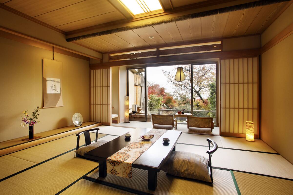 Une pièce de style japonais traditionnel, avec un sol recouvert de tatamis, une table basse agrémentée d’un chemin de table et des portes coulissantes donnant sur un jardin.
