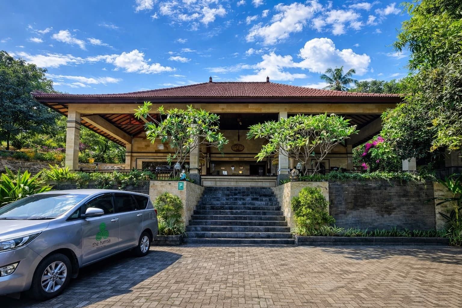 A building with a covered entrance, a car parked in front, and a paved driveway.