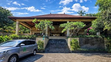 A building with a covered entrance, a car parked in front, and a paved driveway.