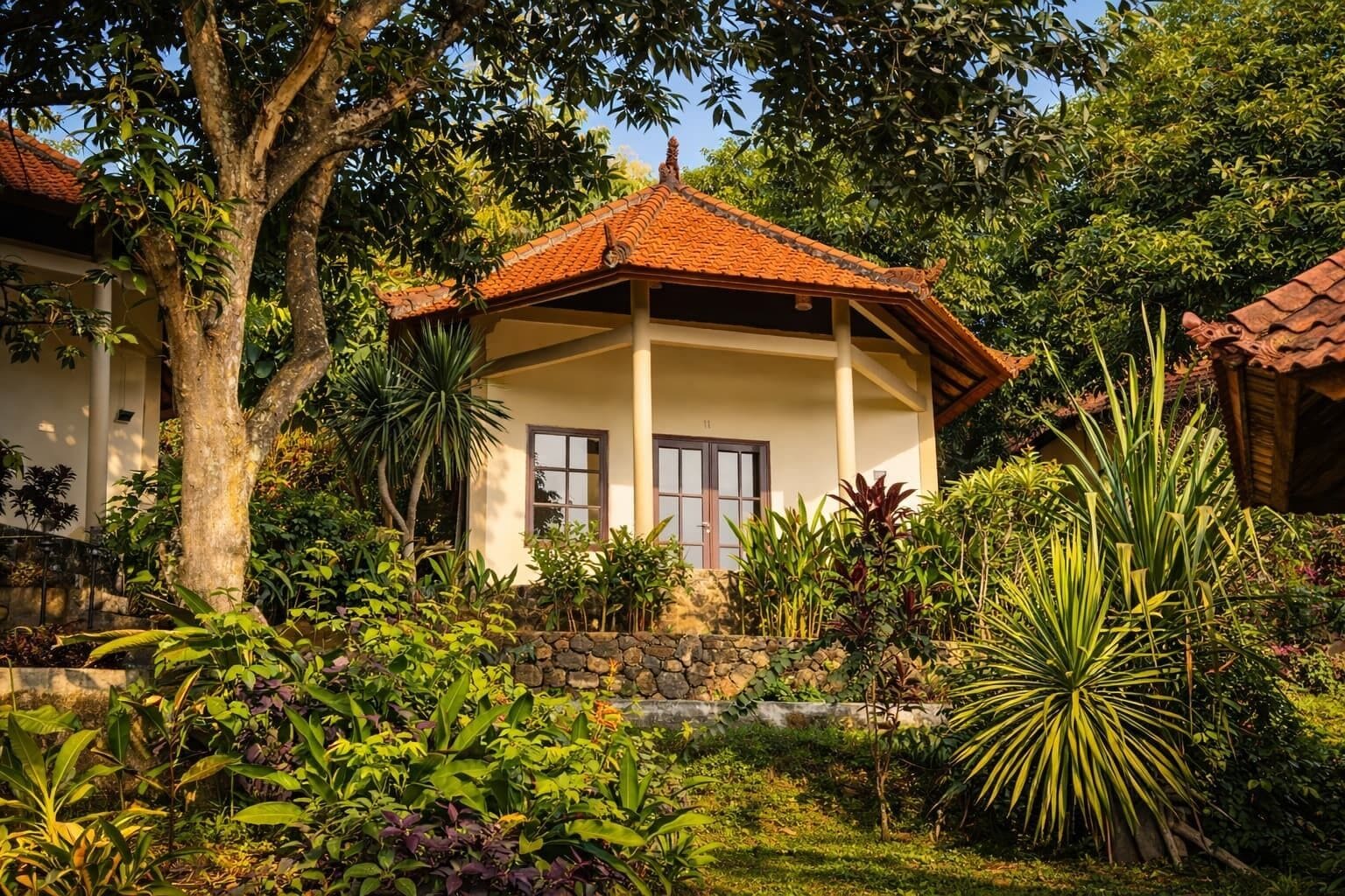 A house with a tiled roof, a stone wall, and a garden with various plants.