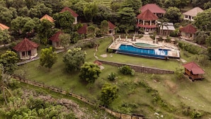 Un resort con varias edificaciones, piscina y abundante vegetación.