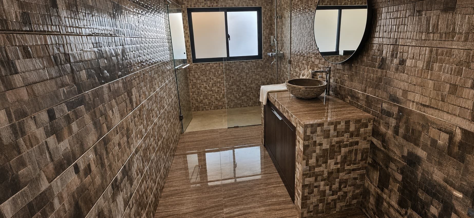 A bathroom with a tiled wall, a sink with a bowl, and a mirror.