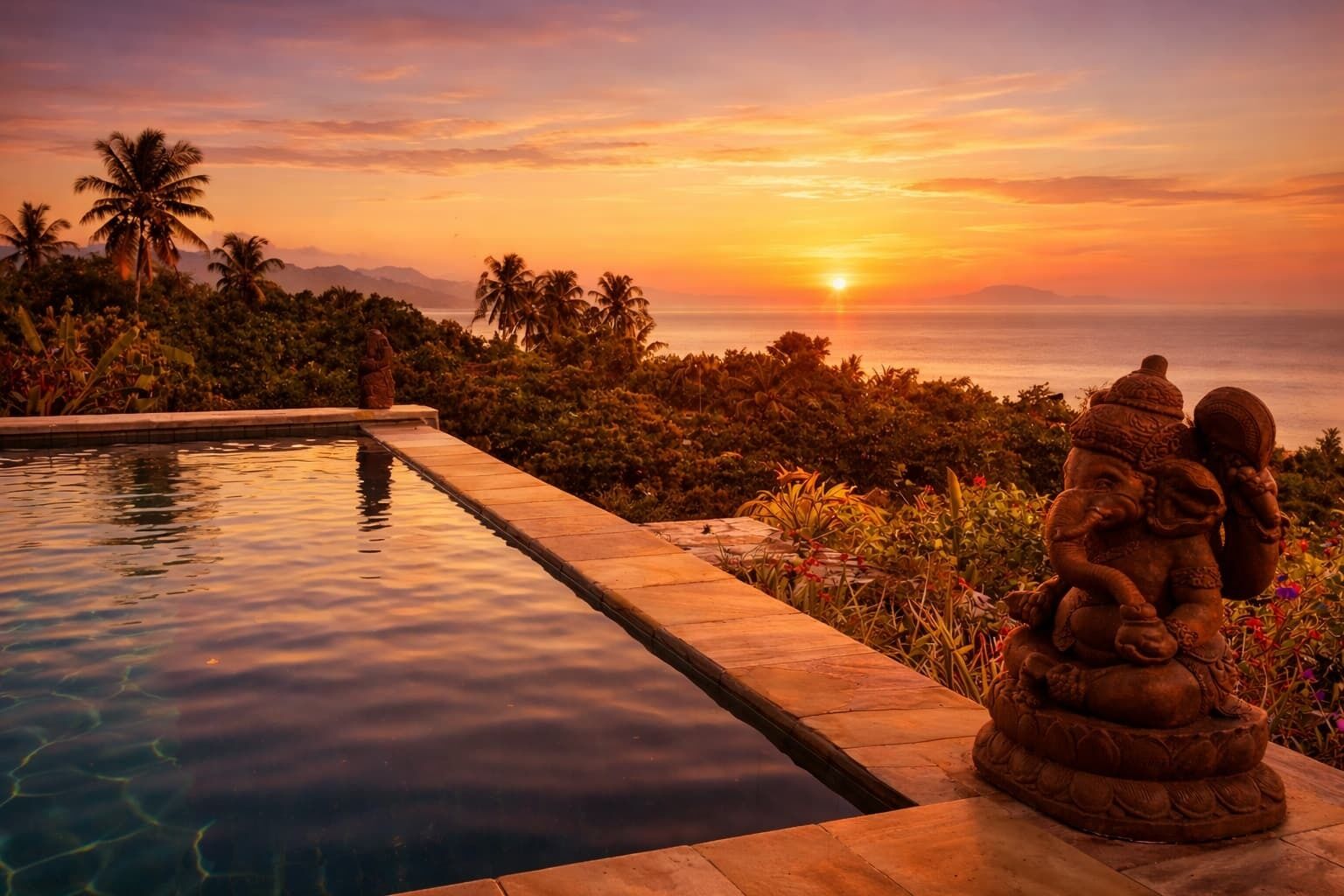 A pool with a statue, palm trees, and a sunset view.