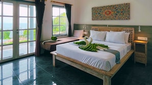 Un dormitorio espacioso con una cama grande, vistas al mar a través de las ventanas y un adorno decorativo en la pared.