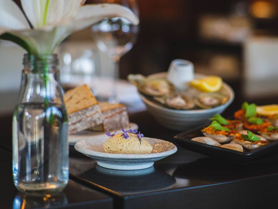 A dining table with various dishes, including seafood and bread, and a vase with flowers.