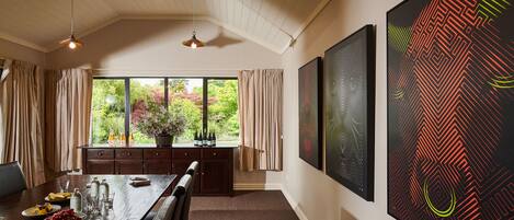 A dining area with a wooden table, chairs, and a view of greenery outside.