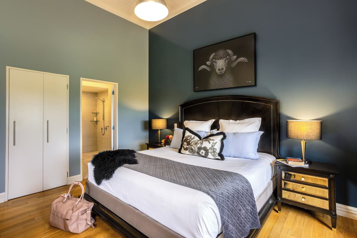 A bedroom with a bed, bedside tables, a nightstand, a wall-mounted artwork, and a wardrobe.