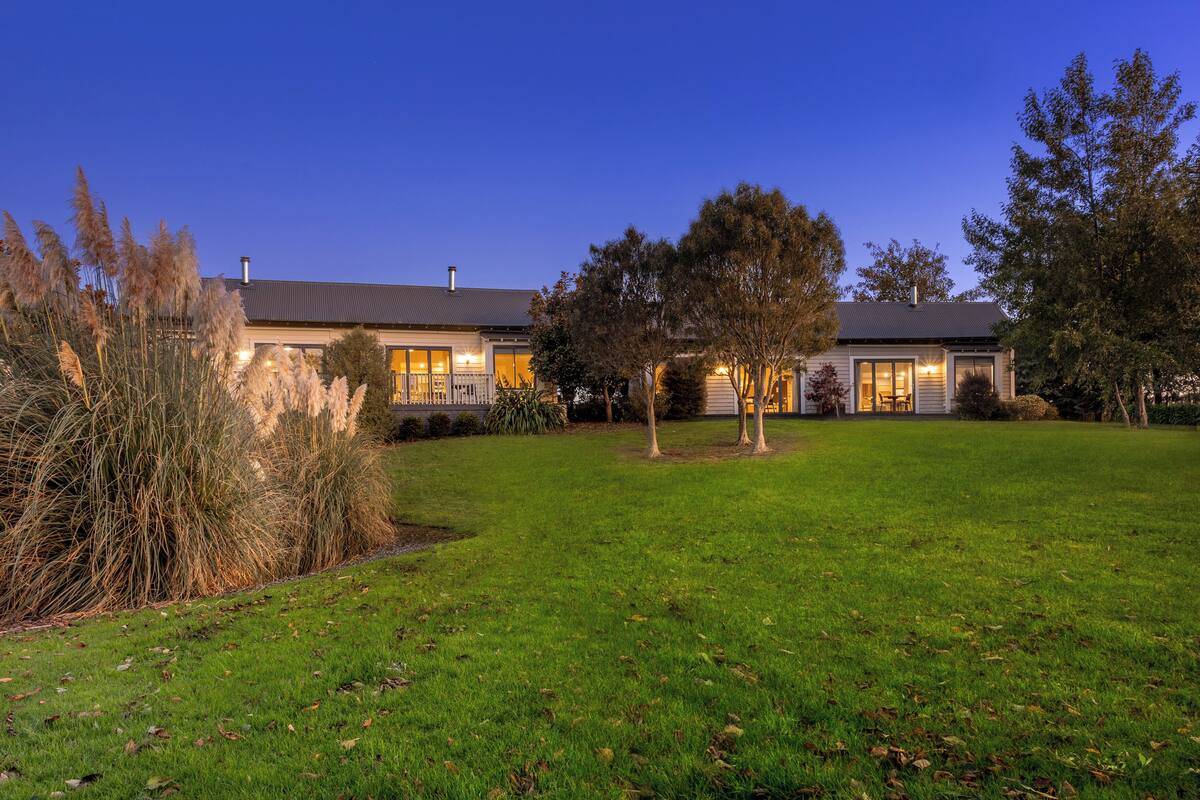 A two-story house with a well-maintained lawn and a small garden area.