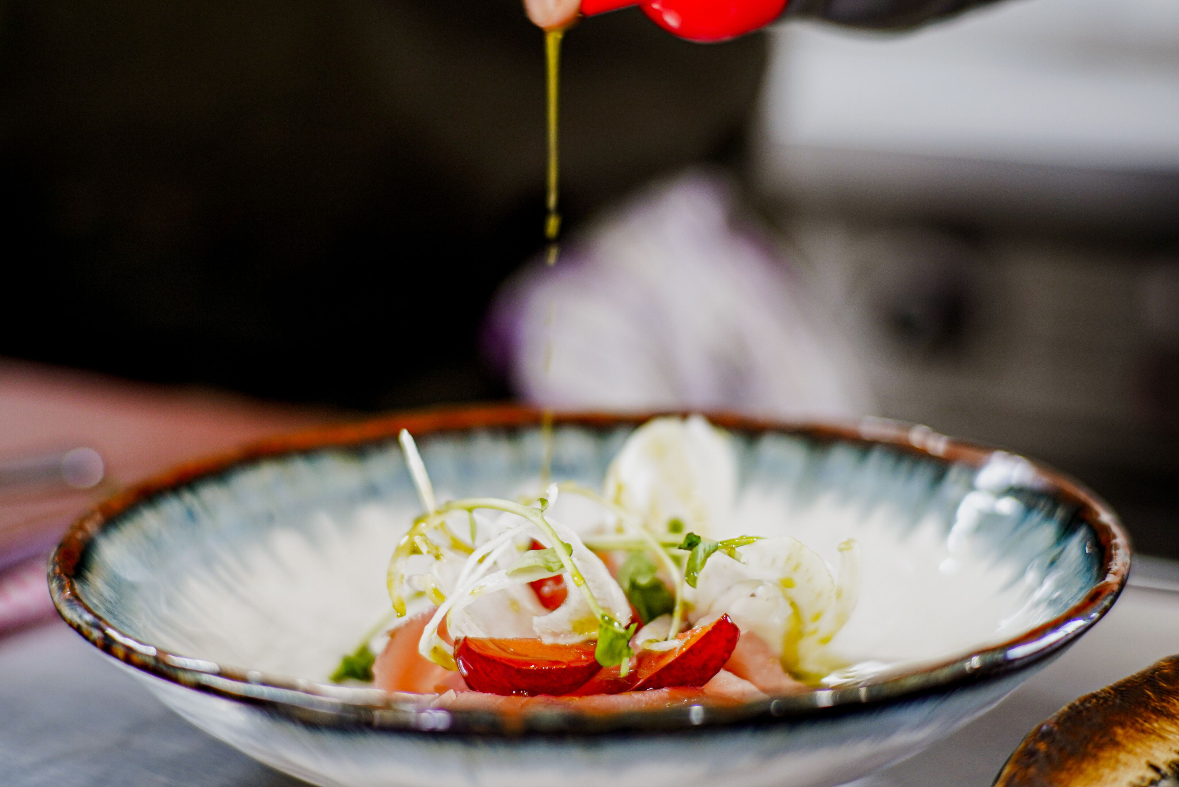 A bowl of food with a sauce being poured over it.
