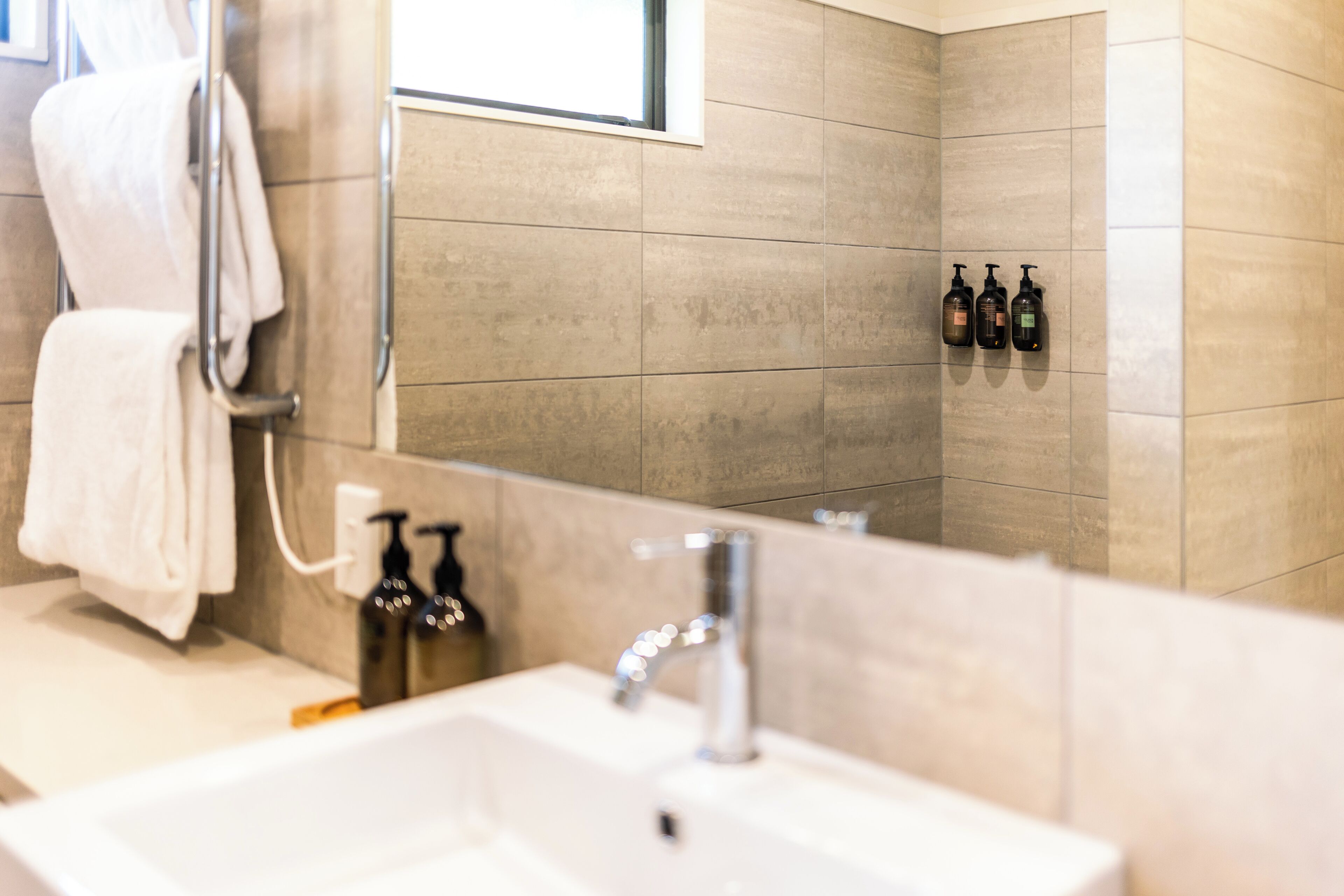 A modern bathroom with a white sink, a mirror, and a towel rack.