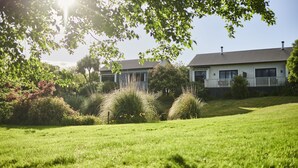 A house with a well-maintained lawn, surrounded by trees and shrubs. - Parehua Resort (Martinborough)