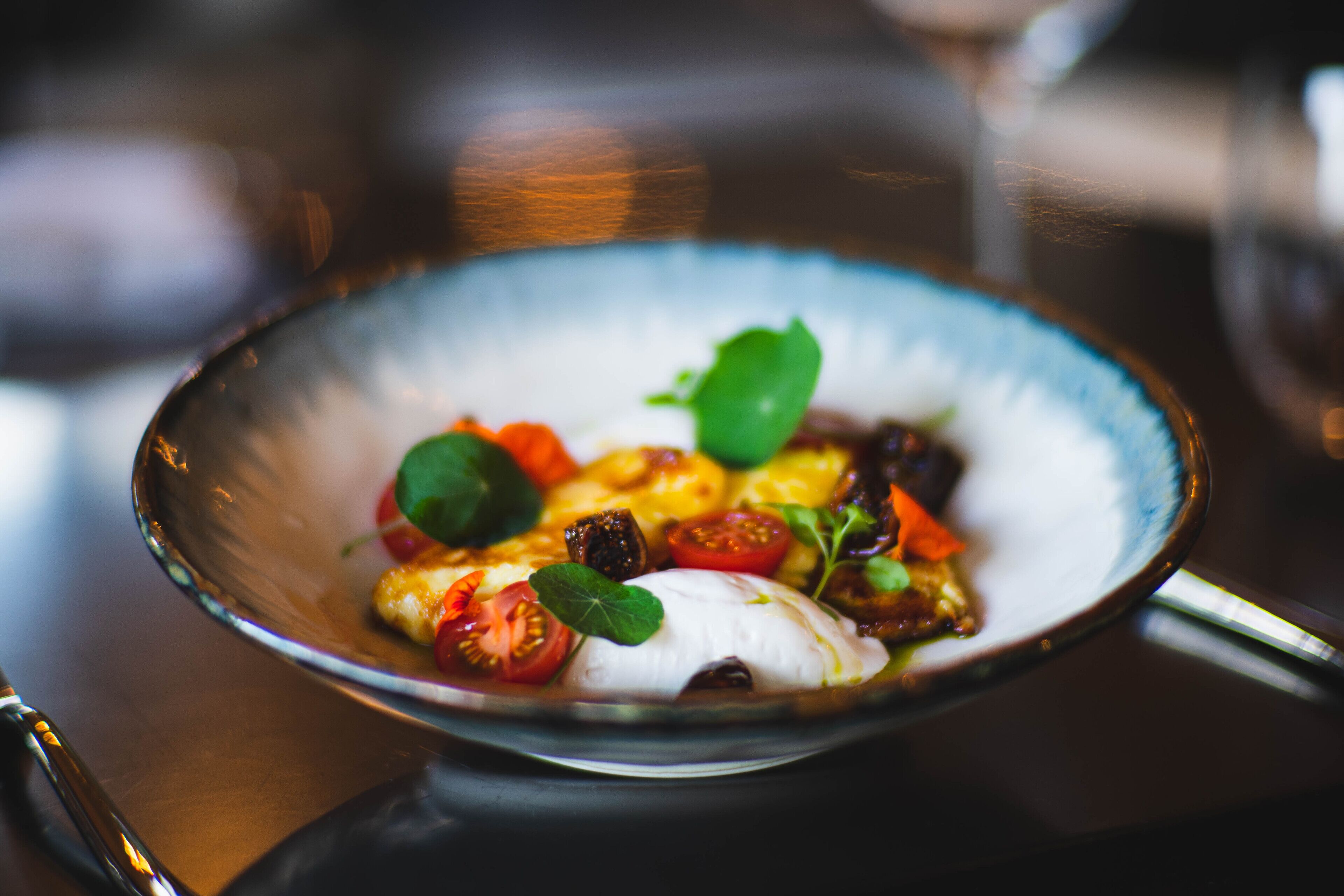 A bowl of food with various vegetables and a green leaf garnish.