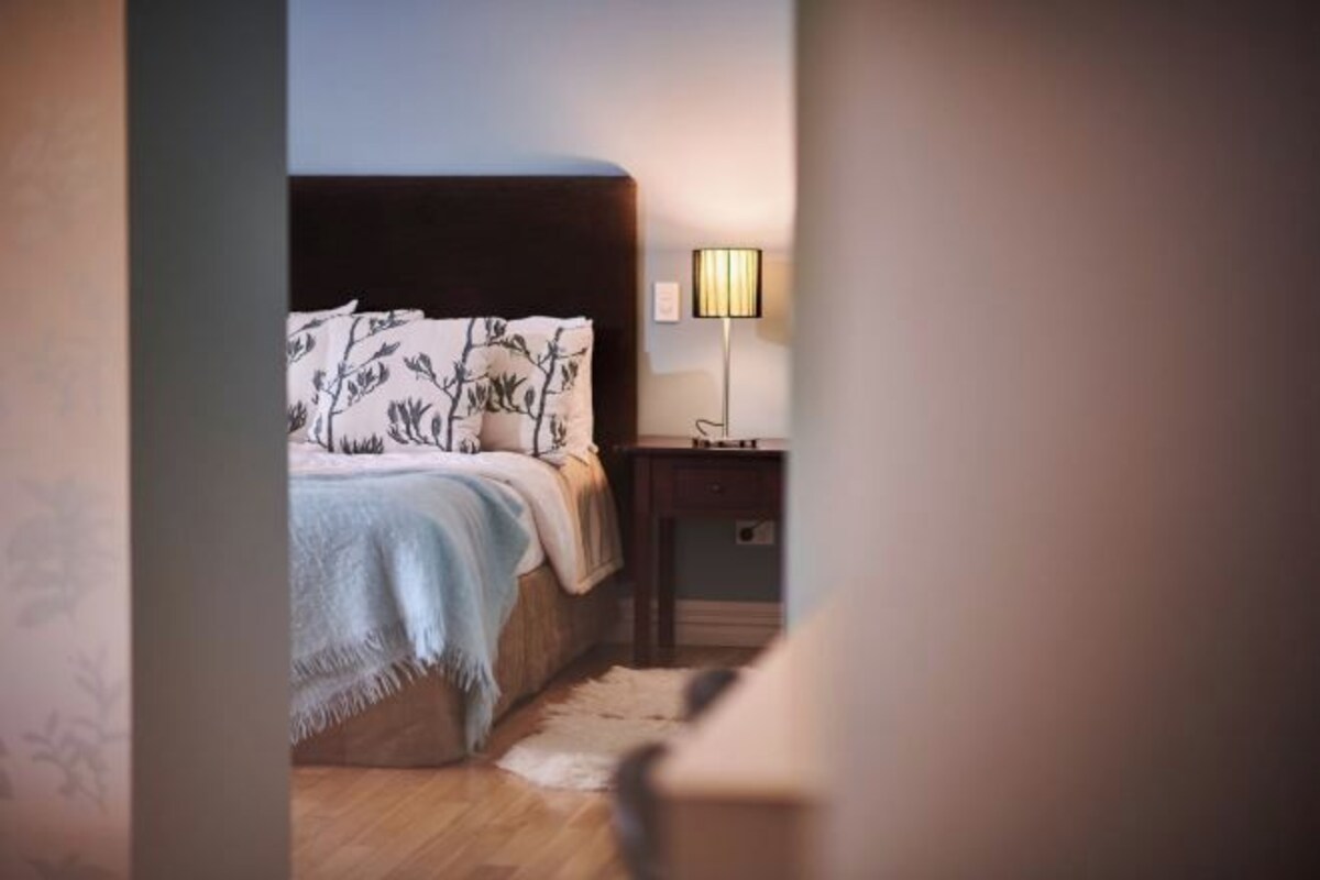 A bedroom with a bed, a nightstand, and a lamp.