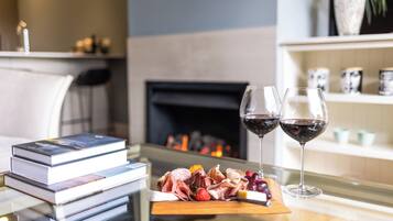 A table with a book stack, a charcuterie board, and two glasses of red wine.