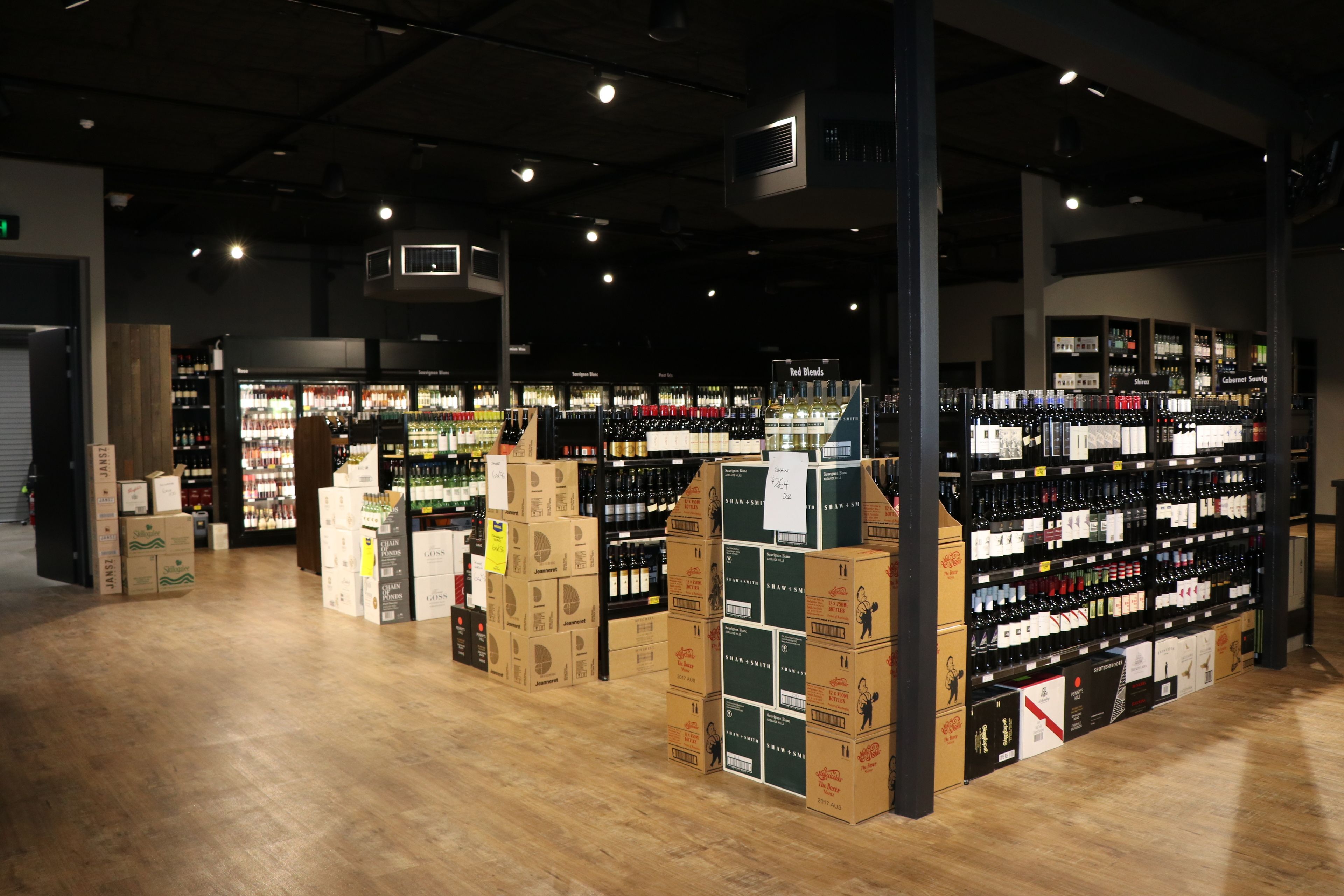 Una amplia tienda con suelo de madera y estanterías repletas de diversos productos.