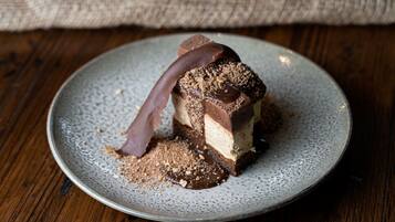 A dessert on a plate with a chocolate drizzle and crumbs on top.