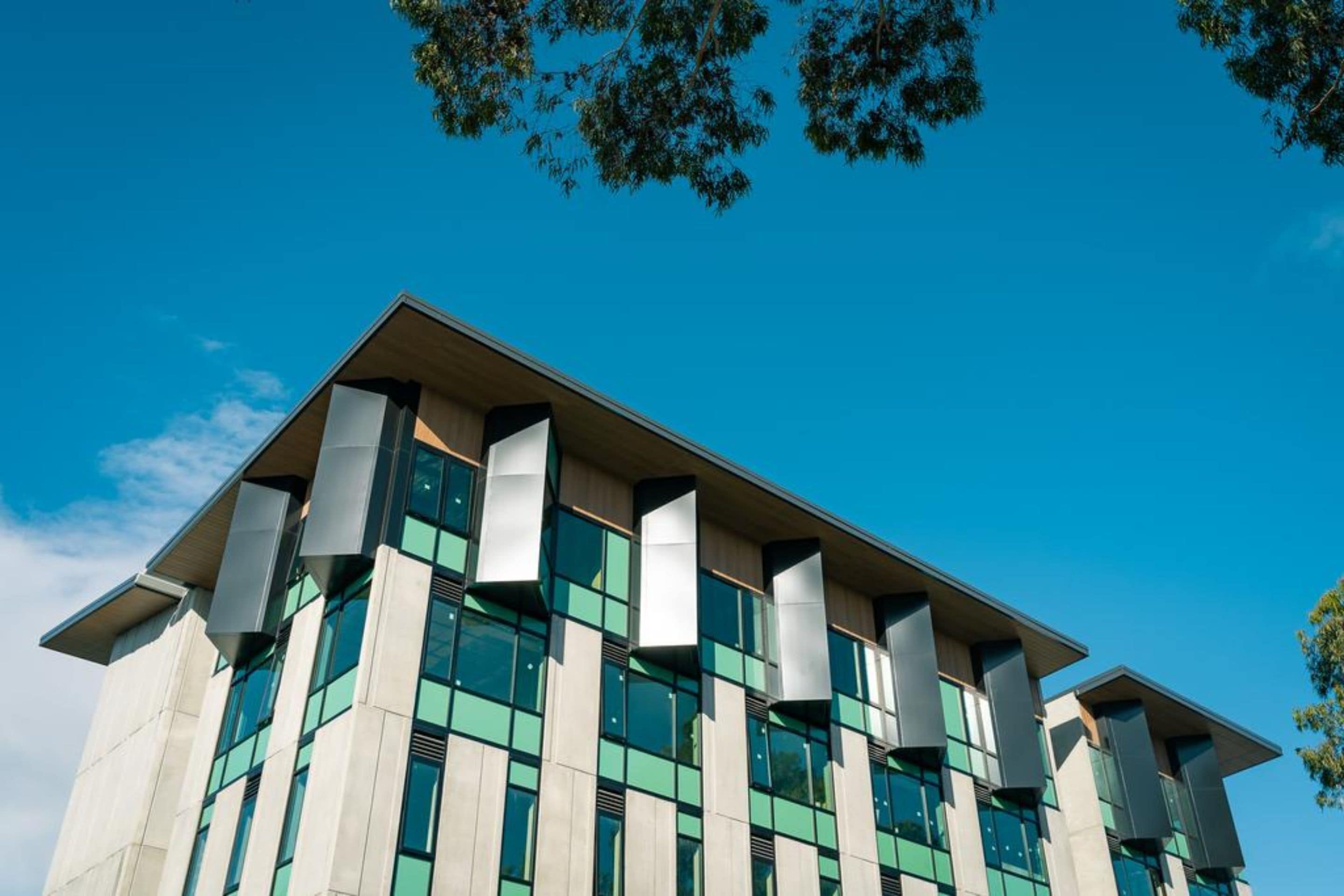 A modern building with a flat roof, large windows, and a symmetrical facade.