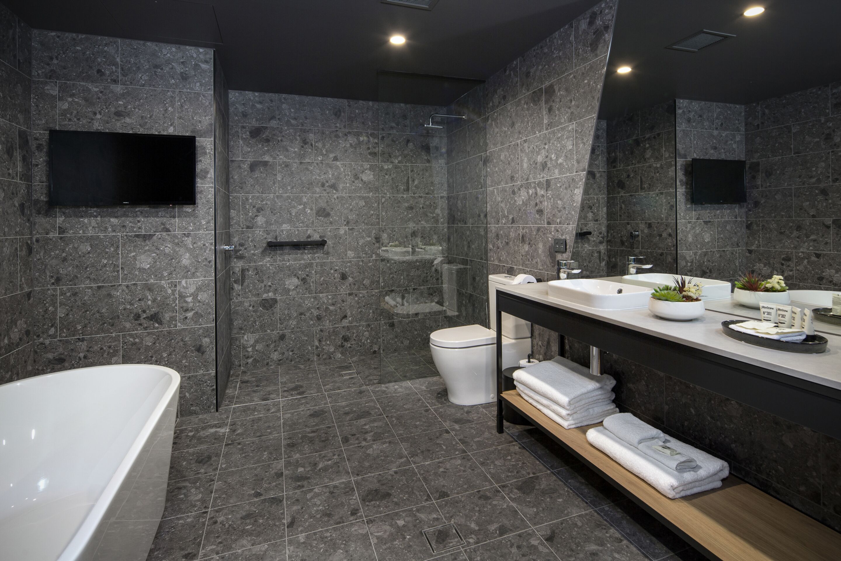 A modern bathroom with a freestanding bathtub, a large mirror, a sink with a vanity, and a shower area.