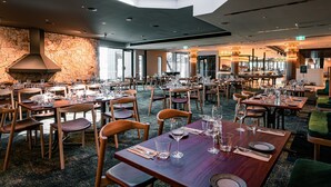 Un restaurante espacioso con numerosas mesas, sillas de madera y una pared de piedra.