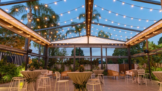Un patio al aire libre con luces colgantes, mesas y sillas.