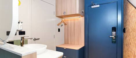 Un baño moderno con un lavamanos blanco, armarios de madera y una puerta azul.