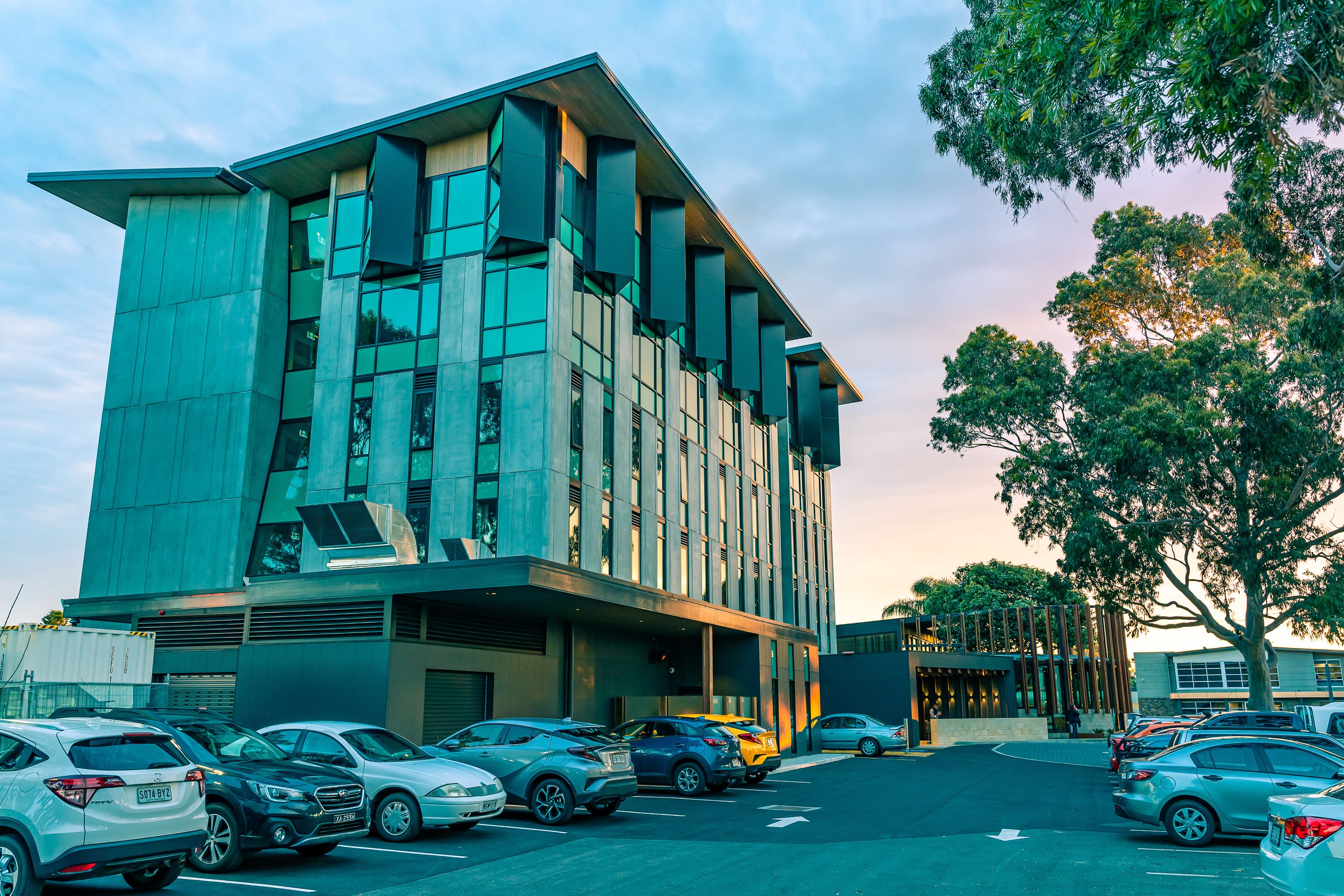 A modern building with a parking lot and several cars.