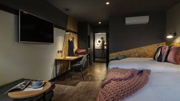 Una habitación de hotel moderna con cama, escritorio, silla, televisor y aire acondicionado instalado en la pared.