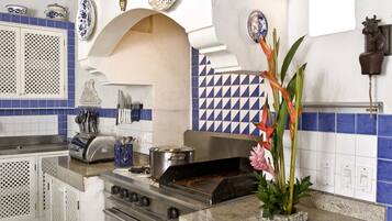 Una cocina con armarios blancos, estufa de acero inoxidable y azulejos azules y blancos.