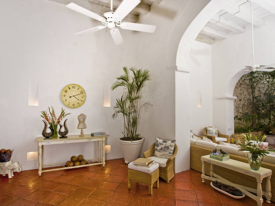 A spacious living room with a large ceiling fan, a potted plant, a wicker chair, and a sofa.