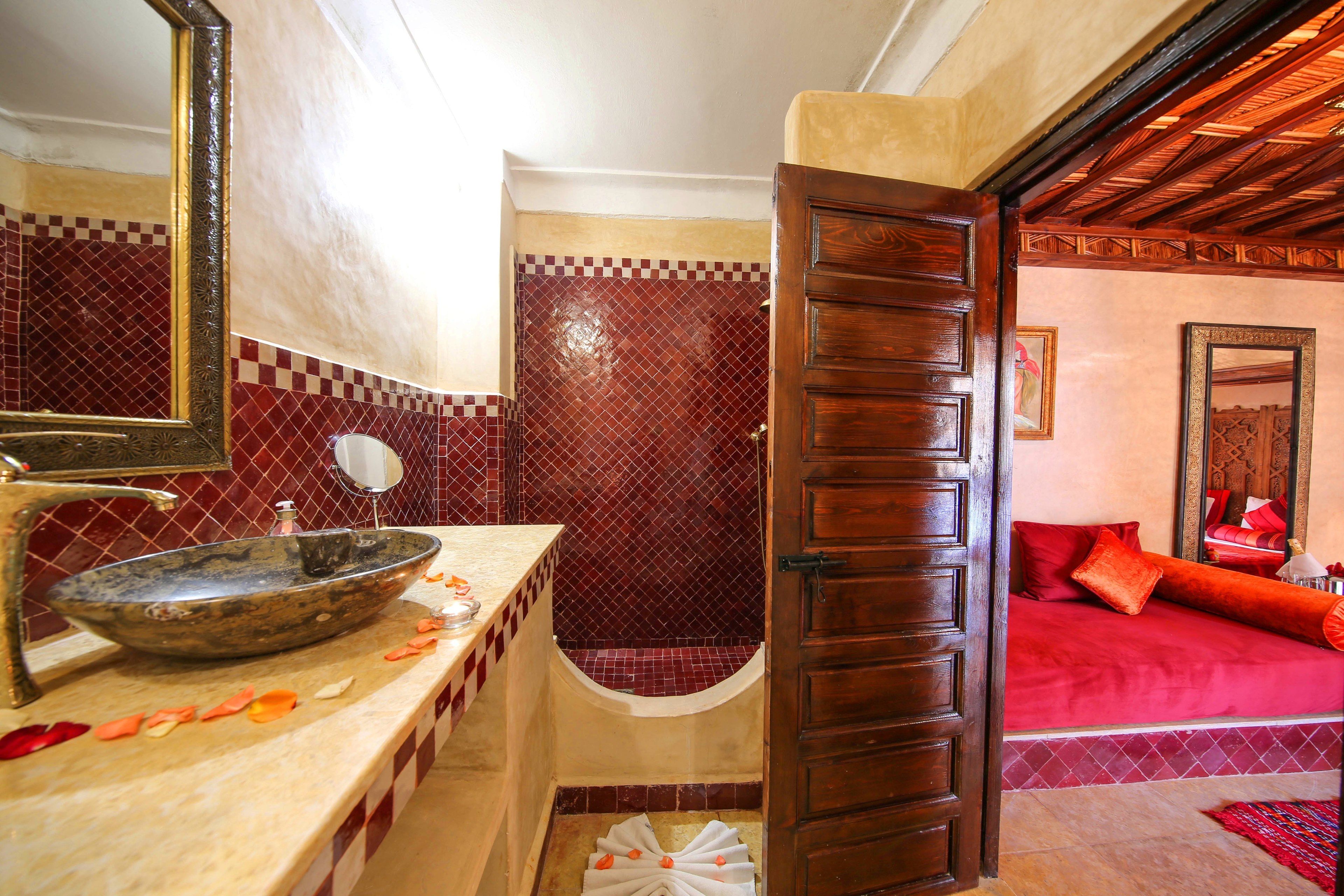 A bathroom with a large basin, a mirror, and a shower area.