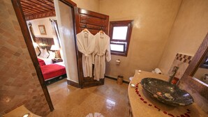 A bathroom with a bathtub, a mirror, a towel rack with robes, and a shower area. - Riad Africa (Marrakech)