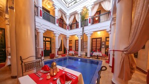 A hotel lobby with a central pool, multiple dining areas, and a high-ceiling atrium. - Riad Africa (Marrakech)