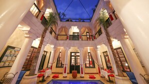 A luxurious indoor pool area with a central fountain, surrounded by columns and potted plants. - Riad Africa (Marrakech)