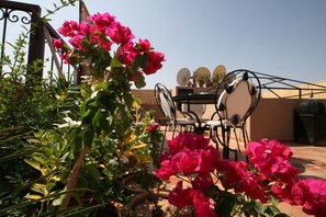 A patio area with a table and chairs, surrounded by potted plants and vibrant flowers. - Riad Africa (Marrakech)