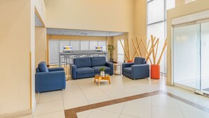 A spacious lobby with a blue sofa set, a small coffee table, and a potted plant.