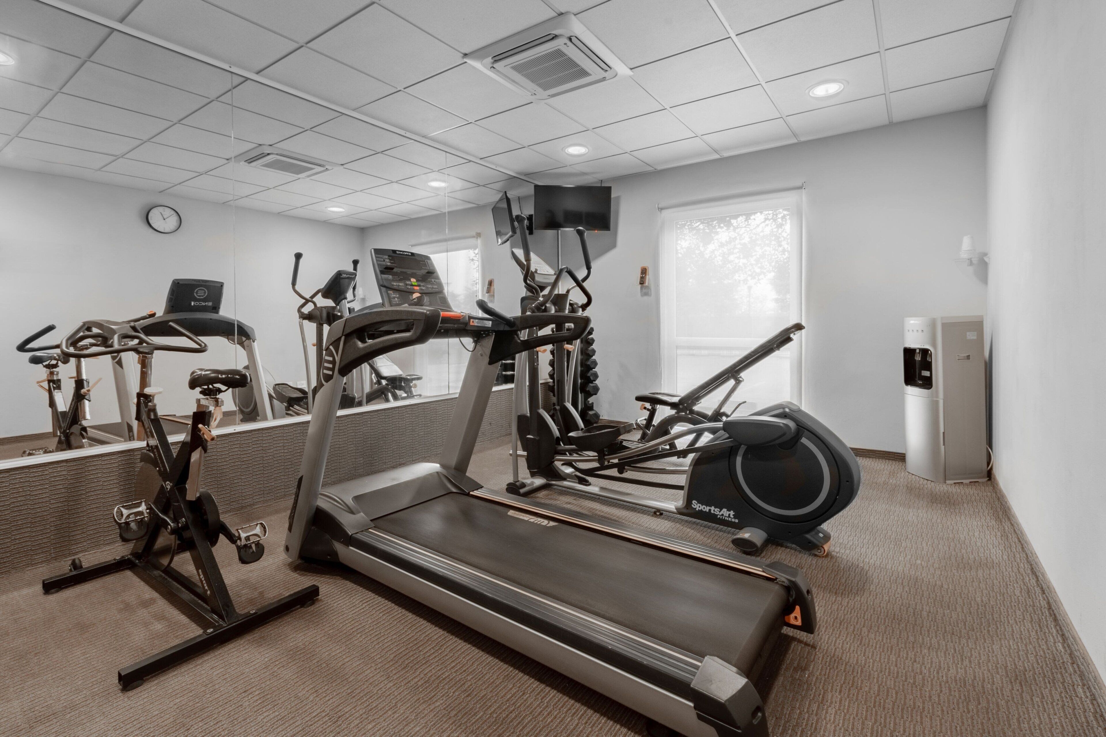 Un gimnasio con cinta de correr, elíptica y bicicleta estática.