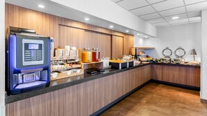 A modern breakfast bar with a coffee machine, various food options, and a counter with a lamp.