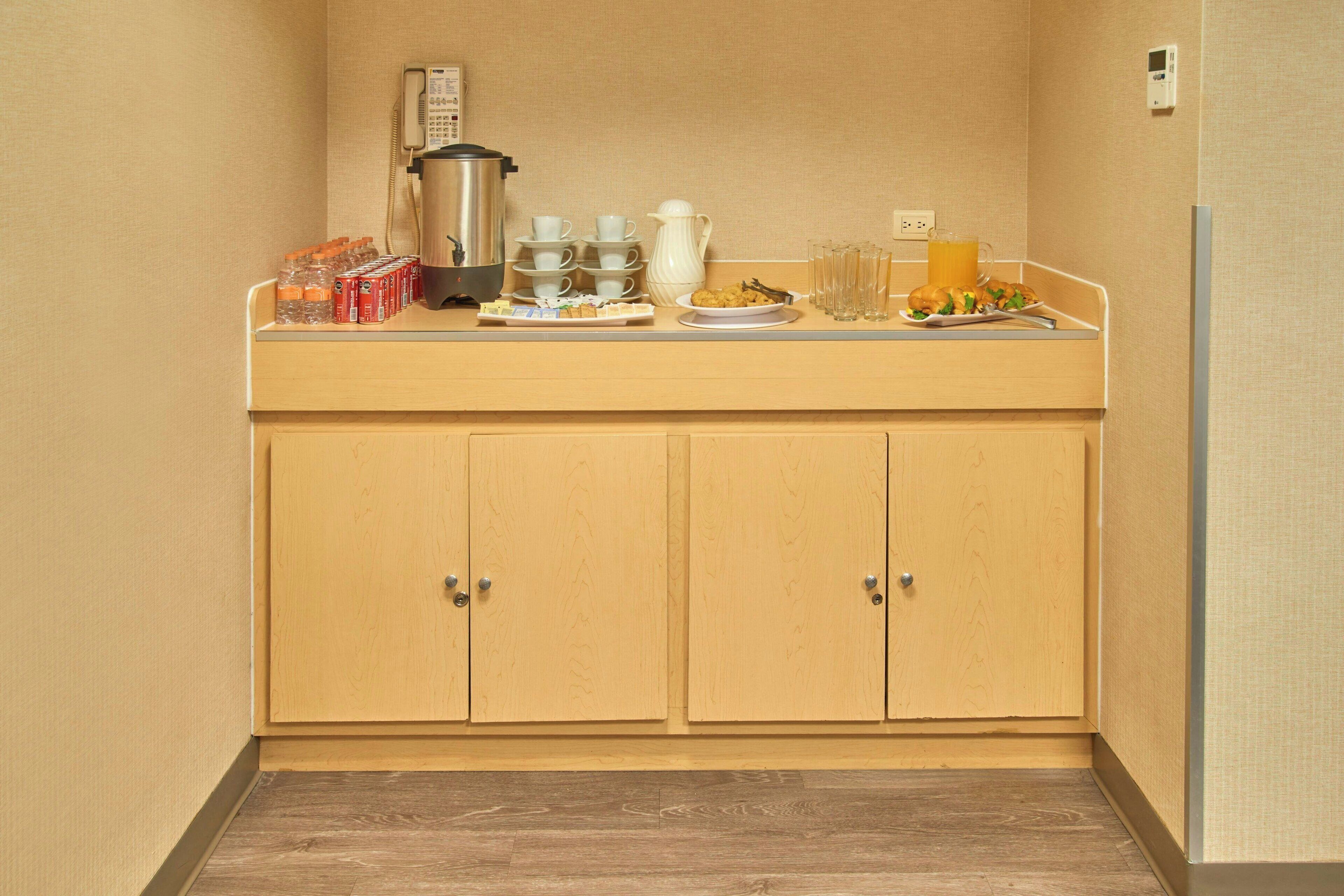 Een kitchenette met een koffiezetapparaat, een waterkoker en diverse ontbijtartikelen op het aanrecht.